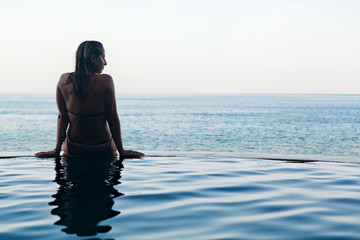 Black silhouette of happy woman on summer beach holiday relaxing in luxury spa hotel in infinity...