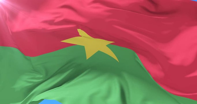 Burkina Faso flag waving at wind in slow with blue sky, loop