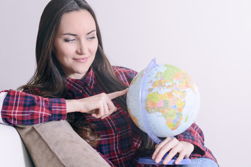 Go on an adventure. Woman dreaming about traveling around the world, looking at the globe in room of the house. Pretty girl study the globe and choose a route of travel