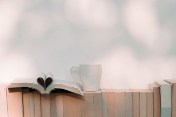 Open book in heart shape with a cup of coffee and books on the shelf - Retro vintage filter effect