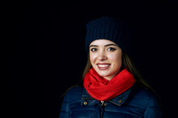 winter portrait of young woman on dark background. Young woman in hat