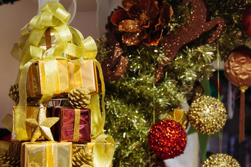 Pile of shiny gift boxes decorated in Christmas tree with Christmas ornament decorations in the background