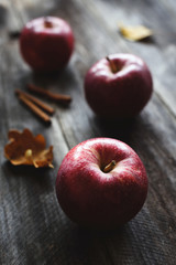 Red apples and cinnamon sticks on wooden background. Autumn food still life