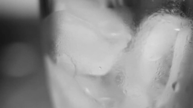 black and white image of ice melting in a glass.  its an abstract blur that shows the textured of the cubes