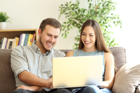 Couple using a laptop together on a couch