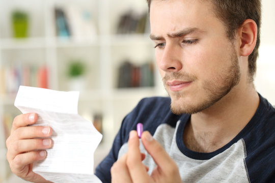 Suspicious man reading leaflet of a pill at home