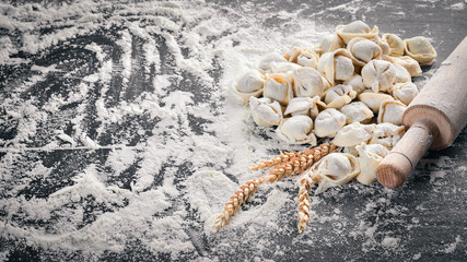 Traditional russian pelmeni, ravioli, dumplings with meat on black concrete background. Top view. Copyspace.
