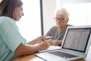 Nurse giving prescription to elderly woman