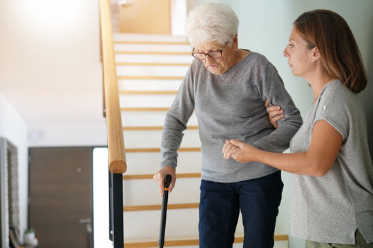 Homecare helping elderly woman going down the stairs