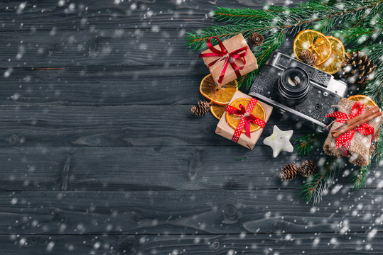 Christmas background with fir, gifts and camera. On a wooden background. Top view Free space for text.