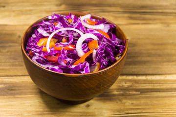 Obraz na płótnie Canvas Red cabbage salad in ceramic bowl on wooden table