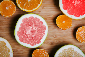 Citrus fruits (orange, lemon, grapefruit, mandarin, lime) on the wooden background. Fruit food background. Sliced Fresh citrus fruit assortment