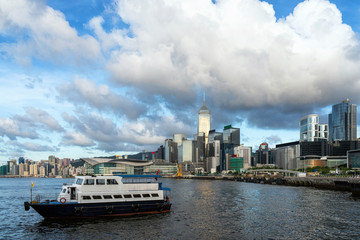 Fototapeta premium Scene of Hong Kong Cityscape river side in the afternoon with transportation boat and smooth cloud, presented the modern construction concept