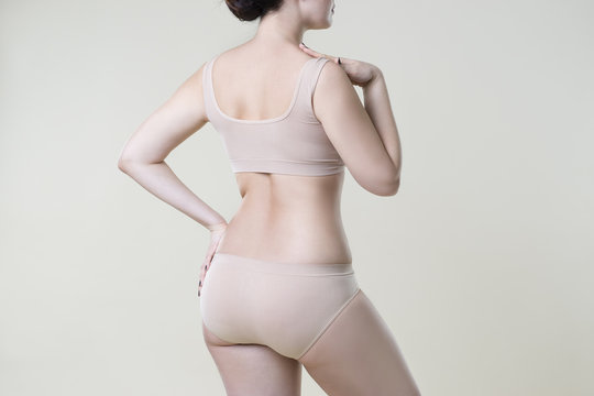 Woman in beige underwear on studio background, cellulite on female body