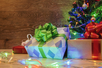 Christmas tree on a wooden background with a garland and gifts