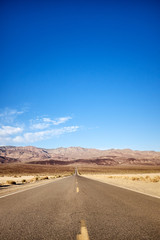 Fototapeta na wymiar Empty straight road leading to mountains in Death Valley, California, USA