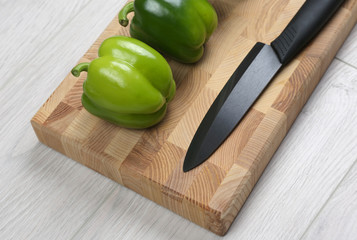 sweet peppers with a ceramic knife on a wooden board