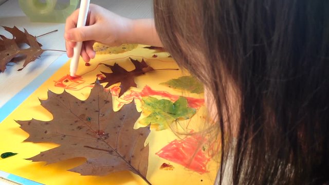 Little girl draws and paints details of the autumn application. Children's Art Project, crafts for kids. 