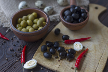 quail eggs, olives, chili and spices on a wooden table