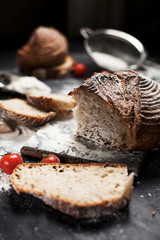freshly baked bread, flour and tomatoes on a wooden board on a table