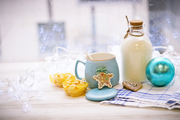 Christmas still-life with an open sugar bowl, white spoon, cookies, pasta, Christmas-tree blue ball, tablecloth in a box on a white wooden table, bright background on a sunny day