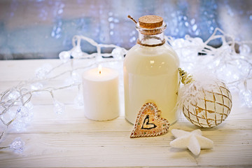On a New Year's wooden table, a candle and a bottle of milk, gnodnevye toys and lights on a Christmas background