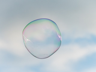 One big soap bubble in front of partly cloudy sky