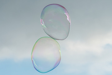 Two big soap bubbles in front of partly cloudy sky