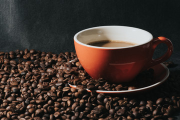 coffee in red cup and coffee beans are the background.