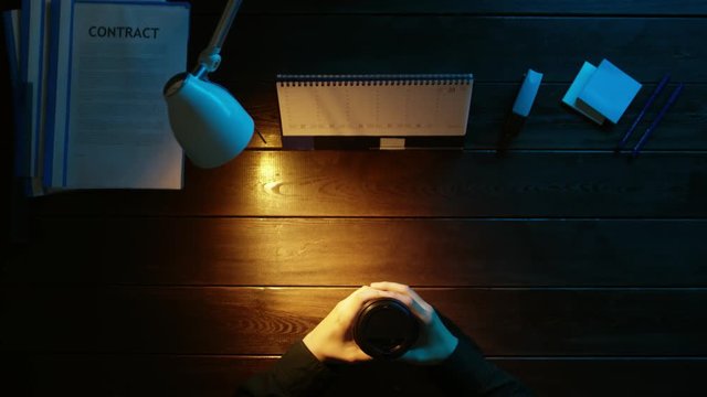 A man is sitting at an office desk and using a phone.