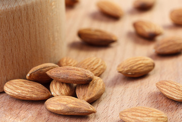 Almonds near a bowl on a wooden background