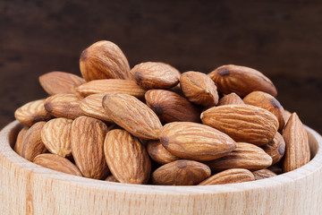Almonds in bowl on wooden background