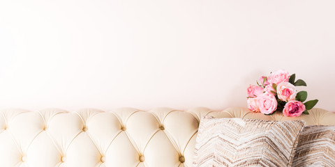 Cream white leather sofa background with pillows and flowers