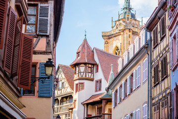 Street view on the beautiful old buildings with cathedral tower in the famous tourist town Colmar in Alsace region, France