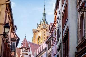 Street view on the beautiful old buildings with cathedral tower in the famous tourist town Colmar in Alsace region, France