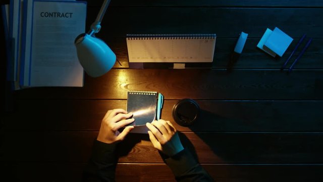 A man is sitting at an office desk and using a phone.
