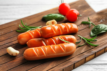 Delicious grilled sausages on wooden board, close up