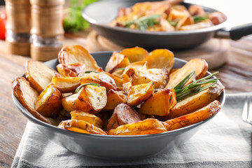 Plate with delicious rosemary potatoes on table