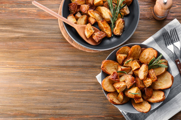 Composition with plate of baked rosemary potatoes on table