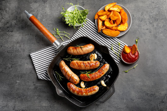 Grill pan with delicious grilled sausages on grey background