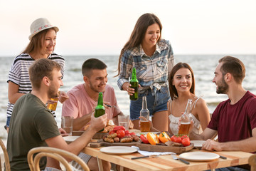 Young people having barbecue party on beach