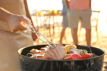 Poster Man cooking steaks and vegetables on barbecue grill, outdoors © Africa Studio