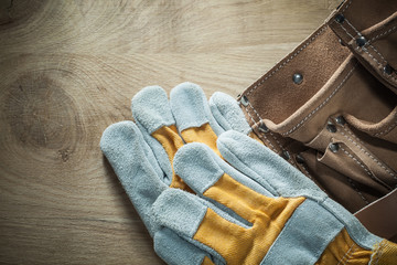 Fototapeta na wymiar Leather building belt safety gloves on wooden board