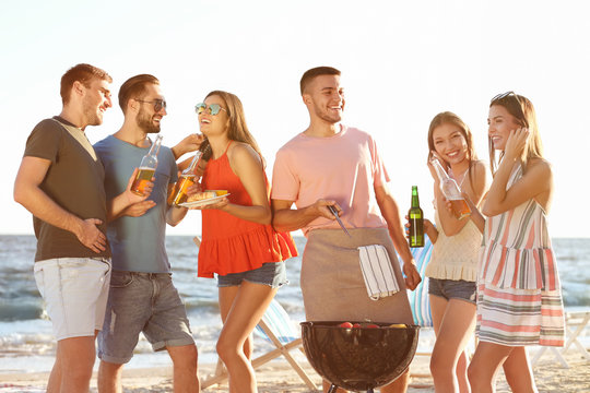 Young people having barbecue party on beach