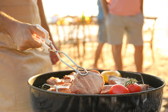 Man cooking steaks and vegetables on barbecue grill, outdoors