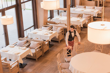 Waiter putting chairs around table