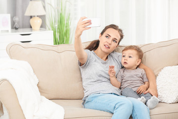 Obraz premium Mother with baby boy taking selfie on sofa at home