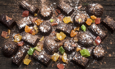 chocolate candies, candied fruits on a wooden background