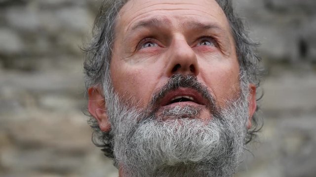 Espressione di uomo anziano con barba grigia guarda verso l'alto