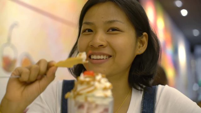 Asian Woman eating ice cream from glass bowl  in cafe 4k UHD (3840x2160)
